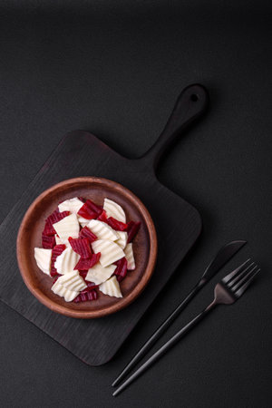 Delicious fresh mozzarella and boiled beets cut into slices on a round ceramic plate on a dark concrete backgroundの写真素材