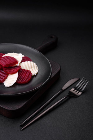 Delicious fresh mozzarella and boiled beets cut into slices on a round ceramic plate on a dark concrete backgroundの写真素材