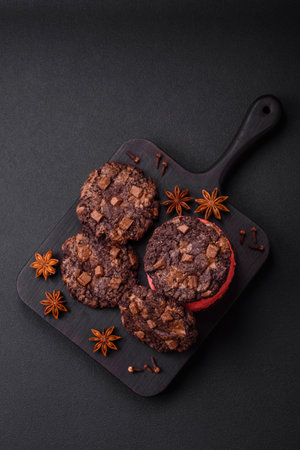 Delicious fresh crispy oatmeal cookies with chocolate and nuts on a black ceramic plate on a dark concrete backgroundの写真素材