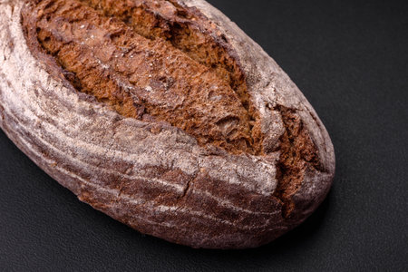 Delicious fresh brown sourdough bread with grains on dark concrete background
