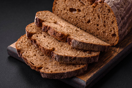 Delicious fresh brown sourdough bread with grains on dark concrete background