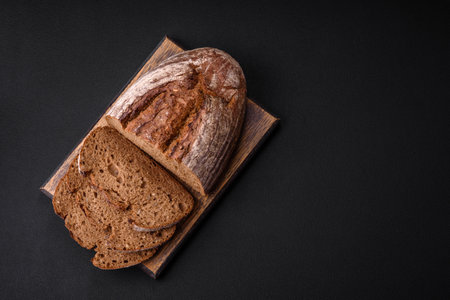 Delicious fresh brown sourdough bread with grains on dark concrete background