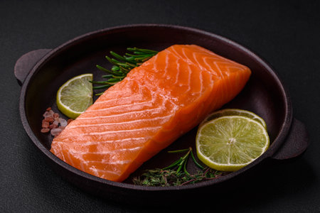 Fresh tasty raw red fish fillet with spices and herbs on a dark concrete backgroundの写真素材