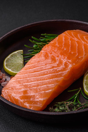 Fresh tasty raw red fish fillet with spices and herbs on a dark concrete backgroundの写真素材