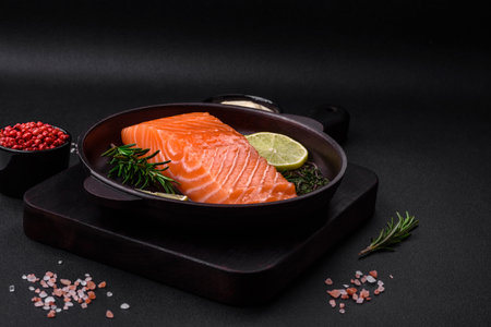 Fresh tasty raw red fish fillet with spices and herbs on a dark concrete backgroundの写真素材