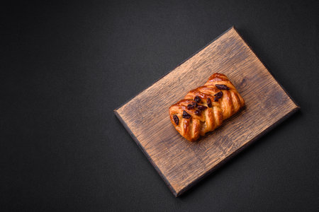 Delicious fresh baked pigtail bun with nuts and syrup on a dark concrete backgroundの写真素材