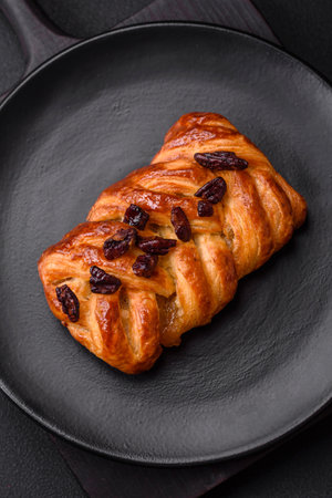 Delicious fresh baked pigtail bun with nuts and syrup on a dark concrete backgroundの写真素材