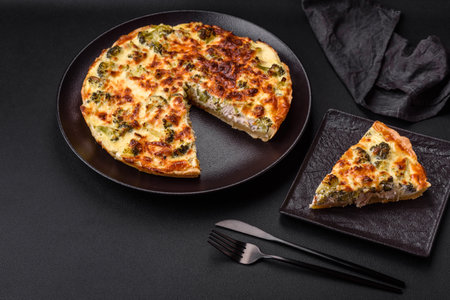 Delicious quiche with broccoli, cheese, chicken, spices and herbs on a dark concrete backgroundの写真素材