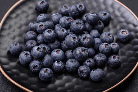 Delicious fresh blueberries on a textural black concrete background. Harvesting seasonal berriesの写真素材