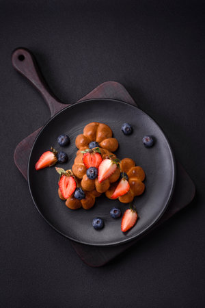 Delicious cupcakes or muffins with raisins and nuts, strawberries and blueberries on a ceramic plate on a textured concrete tableの写真素材