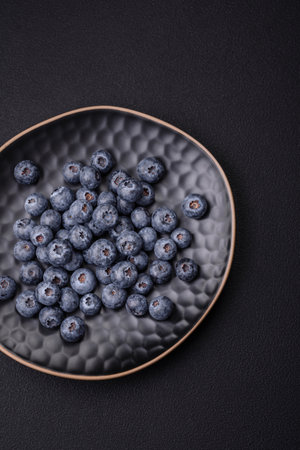 Delicious fresh blueberries on a textural black concrete background. Harvesting seasonal berriesの写真素材