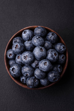 Delicious fresh blueberries on a textural black concrete background. Harvesting seasonal berriesの写真素材