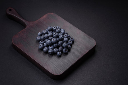 Delicious fresh blueberries on a textural black concrete background. Harvesting seasonal berriesの写真素材