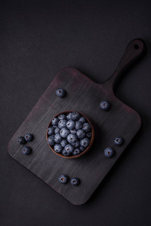 Delicious fresh blueberries on a textural black concrete background. Harvesting seasonal berriesの写真素材