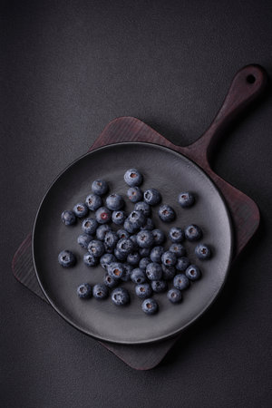 Delicious fresh blueberries on a textural black concrete background. Harvesting seasonal berriesの写真素材