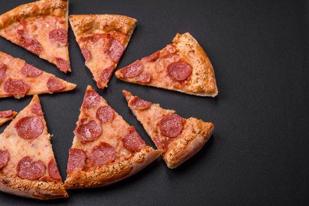 Delicious fresh pepperoni pizza with sesame seeds on the sides on a black concrete backgroundの写真素材