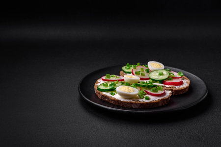 Delicious sandwich or bruschetta with cream cheese radish and green onions on a dark concrete backgroundの写真素材