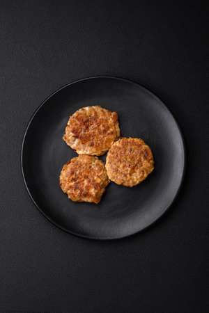 Delicious fresh fried minced fish cutlets with spices and herbs on a dark concrete backgroundの写真素材