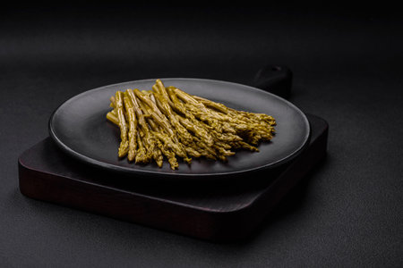 Sprigs of delicious canned asparagus on a black ceramic plate on a dark concrete backgroundの写真素材
