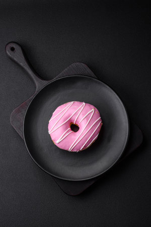 Delicious donut with cream filling and nuts on a dark concrete background. sweet junk foodの写真素材