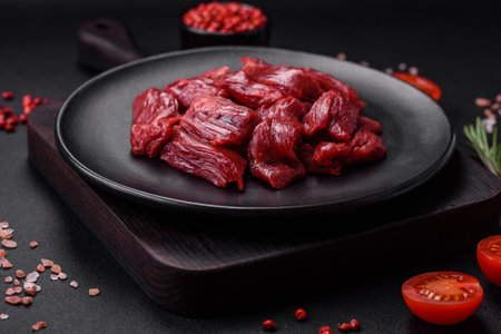 Fresh raw beef with salt, spices and herbs on a dark concrete backgroundの写真素材