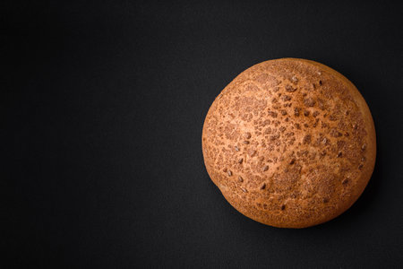 Fresh crispy brown bread with sesame seeds and spices on a dark concrete backgroundの写真素材