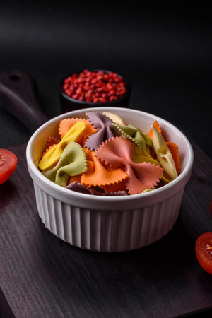 Raw farfalle pasta in different colors on a dark concrete background. Preparing to cook Italian foodの写真素材