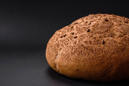 Fresh crispy brown bread with sesame seeds and spices on a dark concrete background