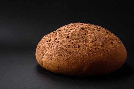 Fresh crispy brown bread with sesame seeds and spices on a dark concrete backgroundの写真素材