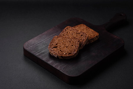 Loaf of fresh crispy brown bread with grains and seeds on dark concrete backgroundの写真素材