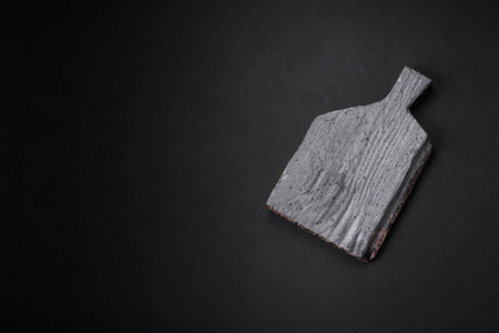Empty wooden cutting board on dark concrete background. Preparing the kitchen table for cooking at homeの写真素材