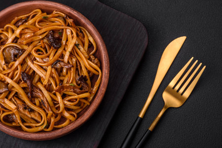 Delicious noodles or udon with mushrooms, salt, spices and herbs on a ceramic plate on a dark concrete backgroundの写真素材