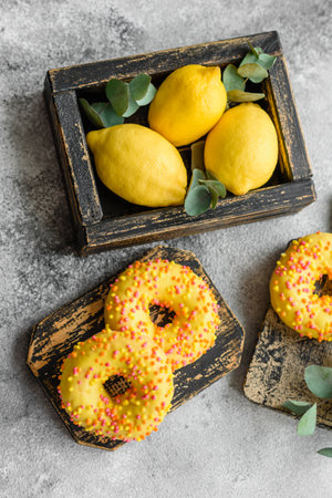 Delicious fresh donuts in yellow glaze with lemon flavor filling on textured concrete backgroundの写真素材