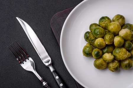 Delicious boiled Brussels sprouts on a ceramic plate on a dark concrete background. Vegetarian foodの写真素材