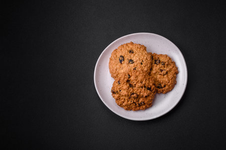 Delicious baked oatmeal raisin cookies on a dark concrete background. Sweets for breakfastの写真素材