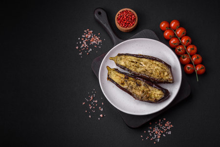 Delicious eggplant cut into two halves baked with salt, spices and herbs on a dark concrete backgroundの写真素材