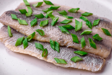 Delicious Atlantic herring marinated with salt and spices in oil on a dark concrete background