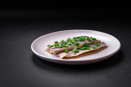 Delicious Atlantic herring marinated with salt and spices in oil on a dark concrete backgroundの写真素材