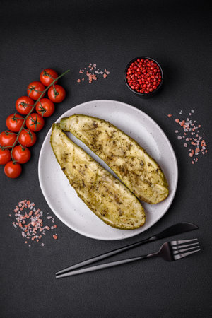 Delicious zucchini cut into two halves baked with salt, spices and herbs on a dark concrete backgroundの写真素材