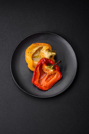 Delicious juicy grilled peppers with spices and herbs on a dark concrete backgroundの写真素材