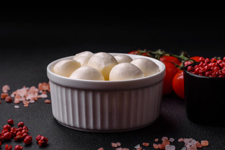 Delicious fresh mozzarella cheese in the form of small balls with salt and spices on a dark concrete backgroundの写真素材
