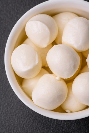 Delicious fresh mozzarella cheese in the form of small balls with salt and spices on a dark concrete backgroundの写真素材
