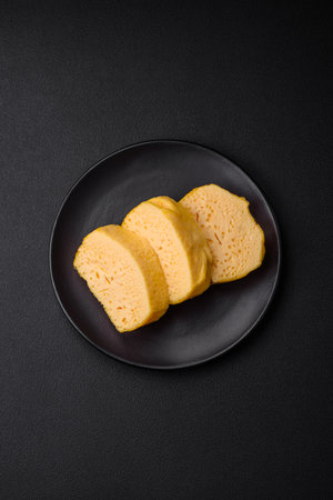 Delicious porous yellow cheese cut in large pieces on a ceramic plate on a dark concrete background