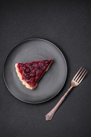 Delicious fragrant sweet pie with cherry berries on a ceramic plate on a dark concrete backgroundの写真素材