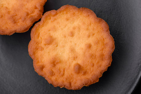 Delicious baked cupcake or tartlet with cheese and raisins on a dark textured background