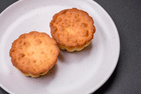 Delicious baked cupcake or tartlet with cheese and raisins on a dark textured background