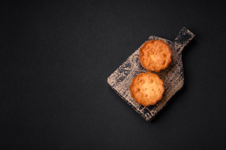 Delicious baked cupcake or tartlet with cheese and raisins on a dark textured backgroundの写真素材