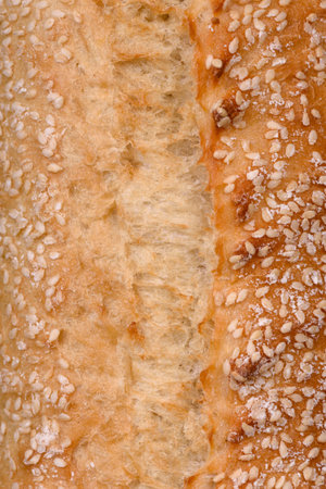 Crispy wheat flour baguette with sesame seeds on a wooden cutting board on a dark concrete backgroundの写真素材