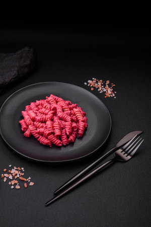 Delicious fusilli pasta with beetroot pesto, parmesan, salt and spices on a dark concrete backgroundの写真素材