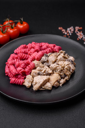 Delicious fusilli pasta with beetroot pesto, parmesan, salt and spices on a dark concrete backgroundの写真素材